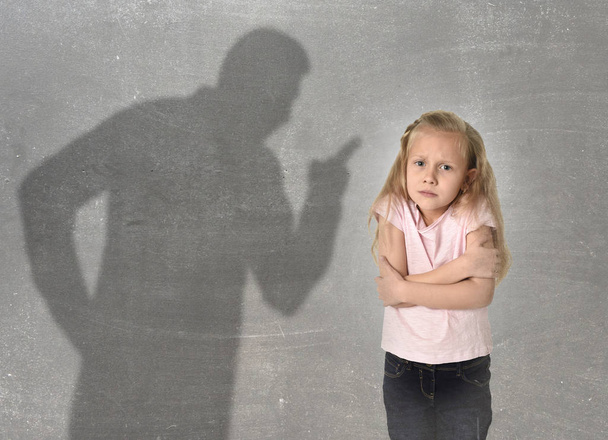father or teacher shadow screaming angry reproving young sweet little schoolgirl or daughter  - Foto, Imagen