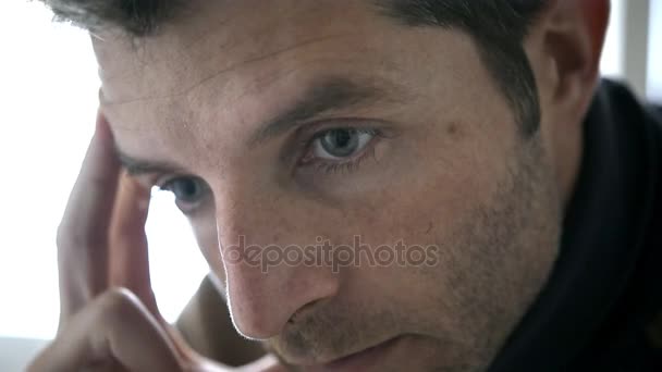 4k 24 fps Handkamera-Tracking auf junge traurige unrasierte Mann zu Hause sitzt vor dem Fenster und sieht traurig und deprimiert leiden Depressionskonzept und Probleme  - Filmmaterial, Video