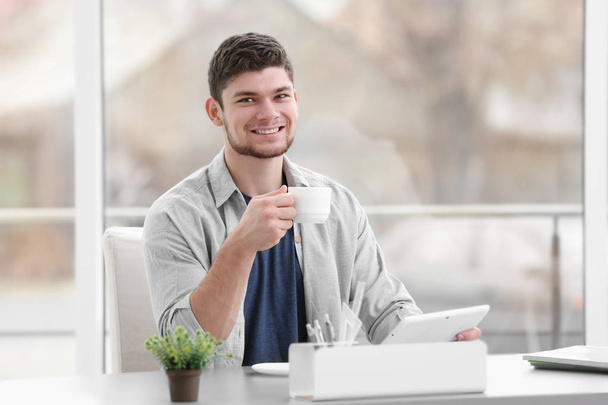 Handsome young man drinking coffee at home - Photo, image