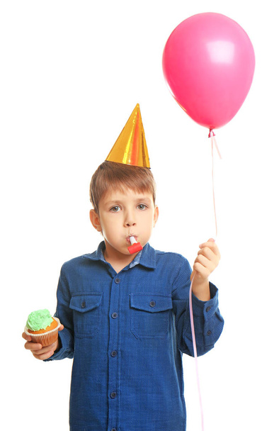Cute birthday boy with tasty cupcake, balloon and party whistle on white background - Zdjęcie, obraz