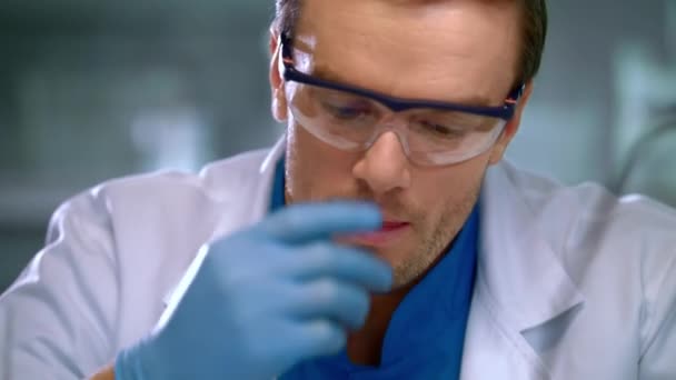 Scientist corrects glasses. Portrait of scientist focused on work - Кадры, видео