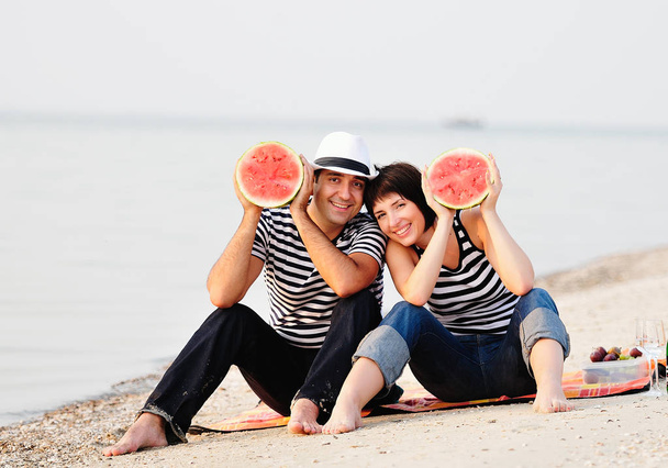 couple assis sur la plage avec pastèque
 - Photo, image