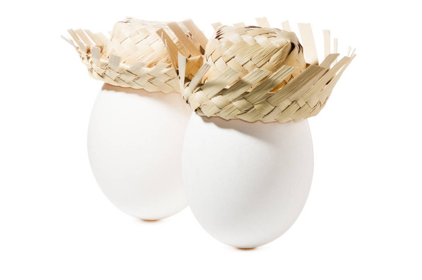 Άσπρα αυγά με ψάθινο καπέλο που απομονώνονται σε λευκό φόντο - Φωτογραφία, εικόνα