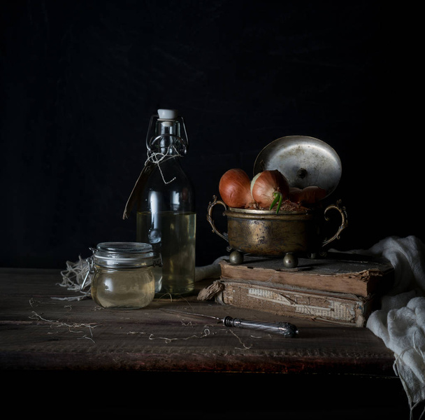 Still life with onions on a wooden table on a dark background - Valokuva, kuva