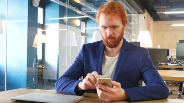 Man Using Smartphone at Work, Red Hairs - Кадри, відео