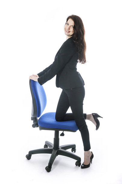 bela secretária morena posa com uma perna na cadeira de escritório
  - Foto, Imagem