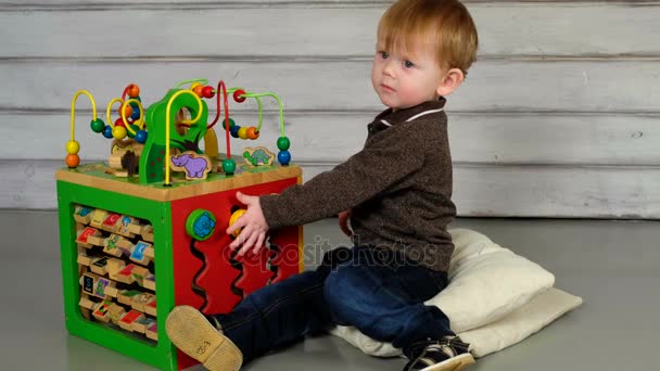 Söpö pieni poika istuu lattialla ja leikkii
 - Materiaali, video