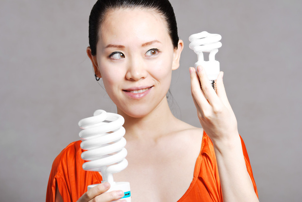 Smiling woman giving energy-saving bulb, isolated on white - Photo, Image