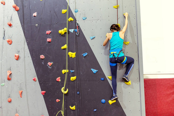 gyönyörű fiatal nő elkezd mászni nagy mesterséges fal - Fotó, kép