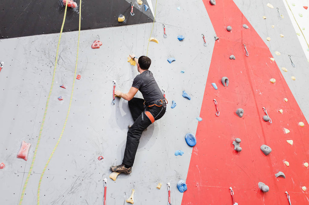 Young man climbing indoor wall and reaching the top - 写真・画像