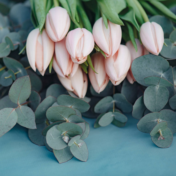 Fresh pink tulip flowers bouquet on eucalyptus leaves, square composition - Photo, Image