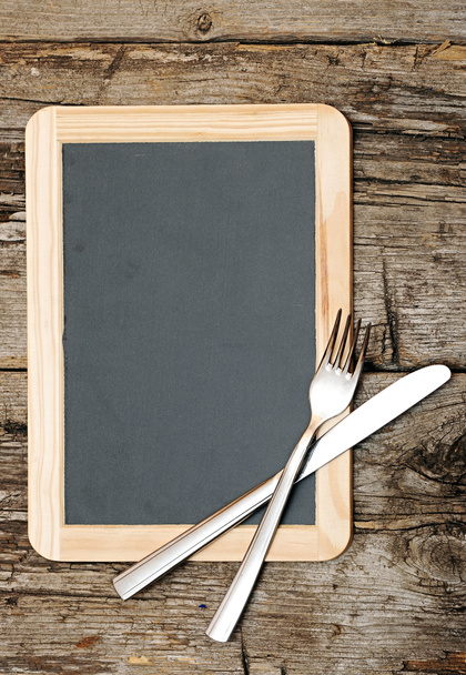 Menu blackboard lying on wooden table with knife and fork - Photo, Image