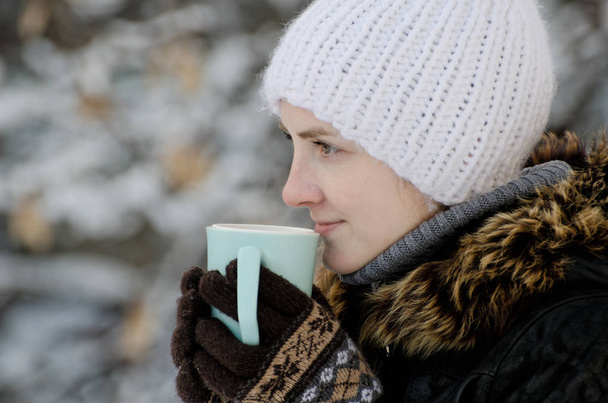 Dziewczyna w zimowe ubrania przy filiżance herbaty, widok z boku, zbliżenie - Zdjęcie, obraz