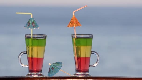 Kaksi lasillista värillinen cocktaileja lähikuva meren taustalla
 - Materiaali, video