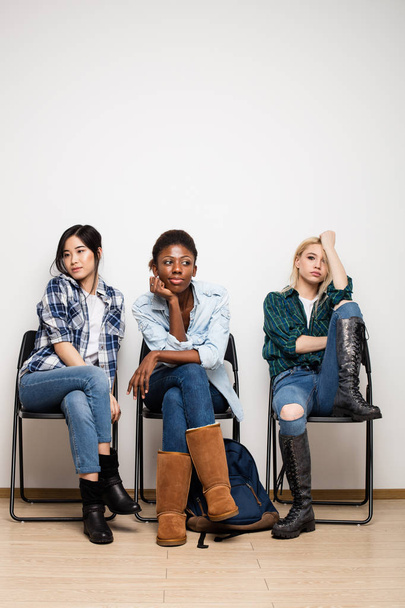 tres diferentes mujeres étnicas esperando en la cola para la entrevista
 - Foto, Imagen