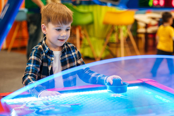 Cute little boy playing air hockey at indoor amusement park - Photo, image