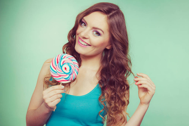 Smiling girl with lollipop candy on teal - Foto, imagen
