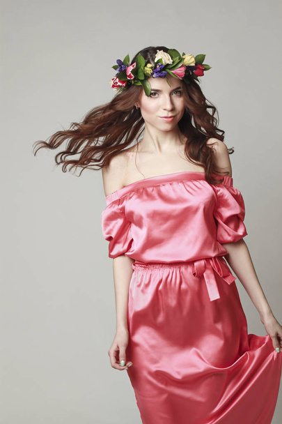 Gentle romantic appearance of the girl with a wreath of roses on her head and a pink dress. Joyful Jolly spring woman. Summer lady in long pink dress - Фото, изображение