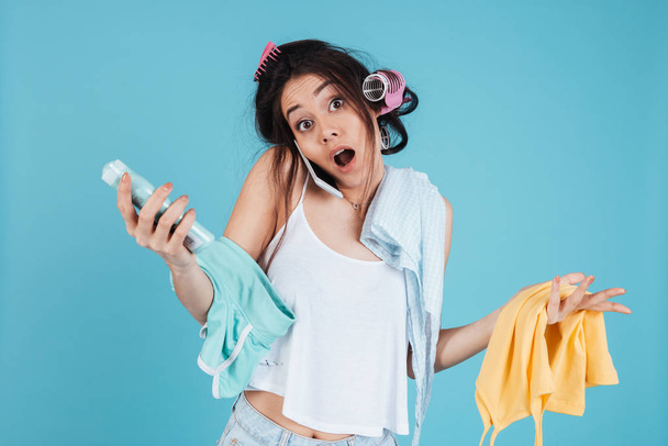 Confused young woman talking by phone and holding clothes - Foto, immagini