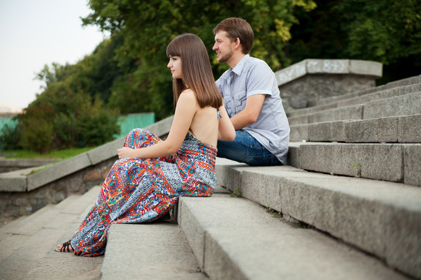 Pari istuu portaissa vihreällä taustalla
 - Valokuva, kuva
