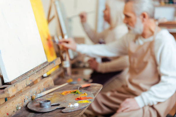 Male artist painting a picture in class - Fotó, kép