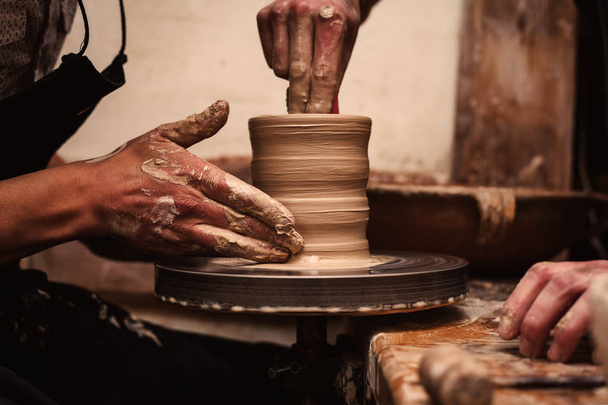 Mãos a trabalhar na roda de cerâmica
 - Foto, Imagem