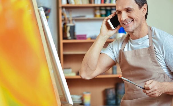 Delighted artist using cellphone in painting studio - Foto, Imagem