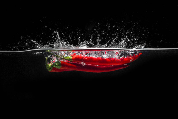 Red hot chili pepper splashing into water - Fotó, kép