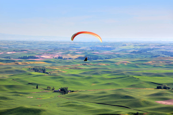 Para zweefvliegtuig omhoog in de hemel boven de glooiende heuvels - Foto, afbeelding