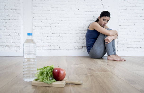  mulher ou adolescente sentada no chão sozinha preocupada em casa sofrendo transtorno alimentar
 - Foto, Imagem