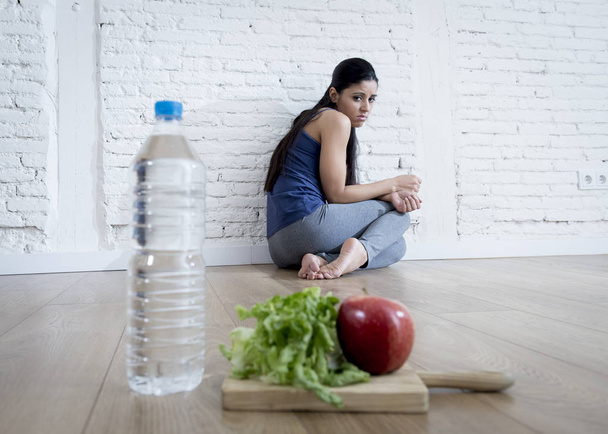  mujer o niña adolescente sentada en el suelo sola preocupada en casa sufriendo un trastorno alimenticio nutricional
 - Foto, imagen