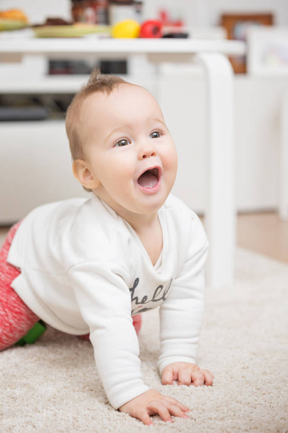 Nove meses de idade bebê menina jogando rastejando no tapete do chão
 - Foto, Imagem