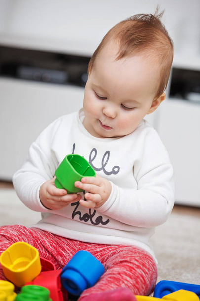 Devět měsíců stará holčička hraje se svými hračkami na podlaze  - Fotografie, Obrázek