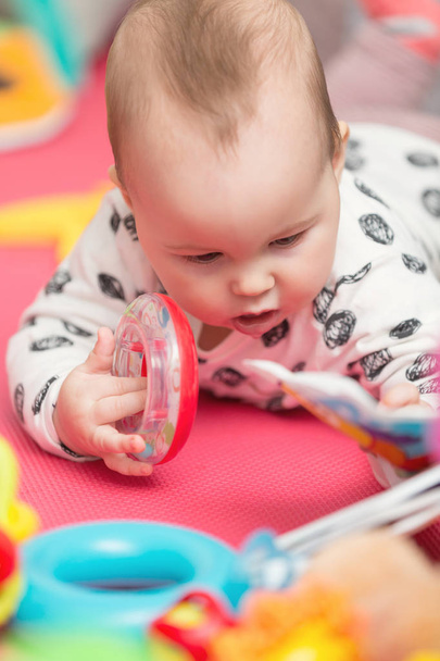 Osm měsíců starou holčičku hraje s barevnými hračkami na podlaze - Fotografie, Obrázek