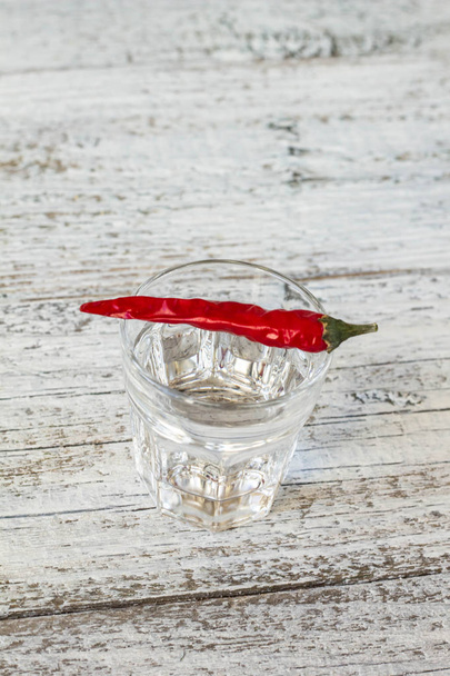 Shot of vodka with pepper on an old wooden table - Photo, Image