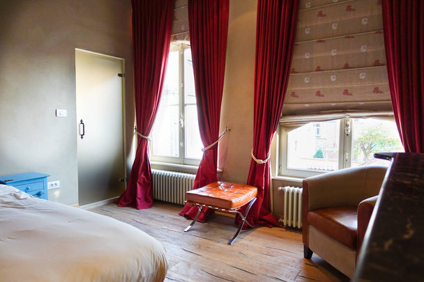 Комфортна спальня з великими вікнами і дерев'яними підлогами
 - Фото, зображення