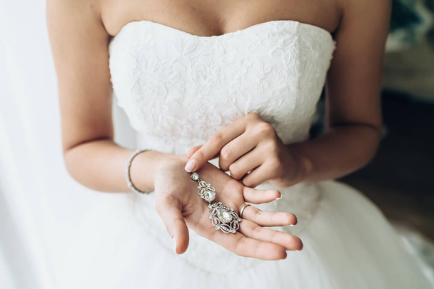 Elegant bride holding silver earrings. Tender hands with jewelry. - Fotoğraf, Görsel