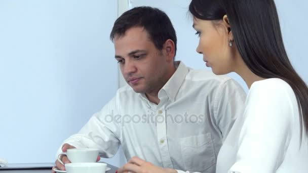 Sick young man sneezing while worried female checking his head for fever and giving him napkin - Πλάνα, βίντεο
