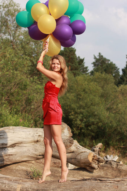 Chica feliz sosteniendo montón de globos de aire de colores en la playa
 - Foto, Imagen