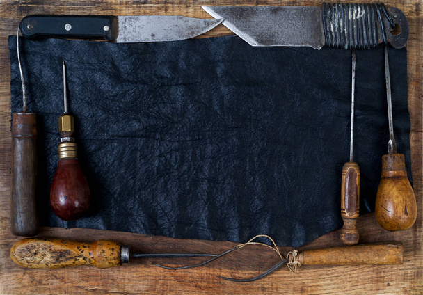 Bőr kézműves eszközök egy fából készült háttér. Craftmans íróasztal. - Fotó, kép