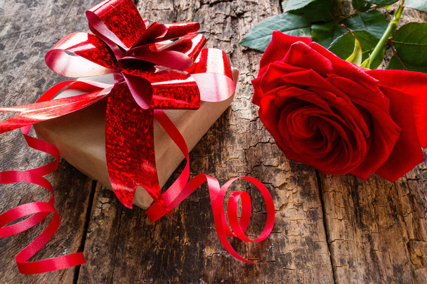 gift and red rose close-up on a wooden background - Фото, изображение