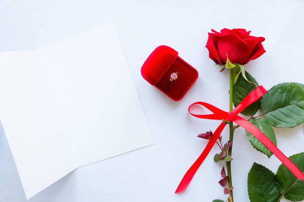 rosa, anel de casamento e um cartão de saudação com espaço para texto sobre fundo branco
 - Foto, Imagem