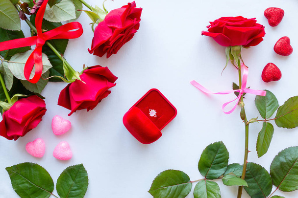 Frame of red roses, leaves, hearts and wedding rings on a white background - Foto, afbeelding