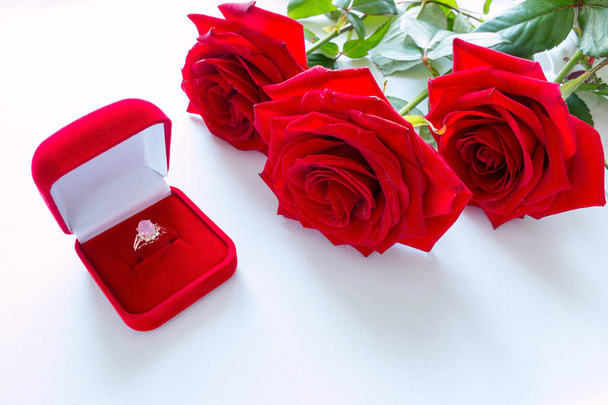 boeket van rode rozen en trouwring close-up - Foto, afbeelding
