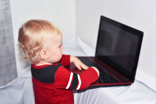Boldog kisfiú piros laptop. - Fotó, kép
