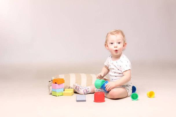 Niño sorprendido sentado y jugando con algunos juguetes
. - Foto, Imagen