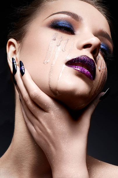 Young woman with creative make-up and violet lips with a gradient and sparkles on the face. Beautiful model with bright nails with rhinestones. - Φωτογραφία, εικόνα