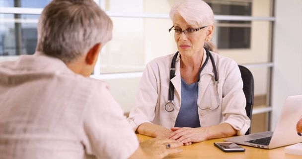 Doctora principal hablando con una paciente anciana en el consultorio
 - Foto, imagen