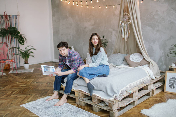 Young hipster couple reading magazine on handmade bed with dream - Zdjęcie, obraz