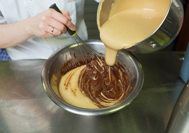 Molho de toffee salgado cremoso sendo misturado e misturado, em uma tigela de rico molho de chocolate escuro
. - Foto, Imagem